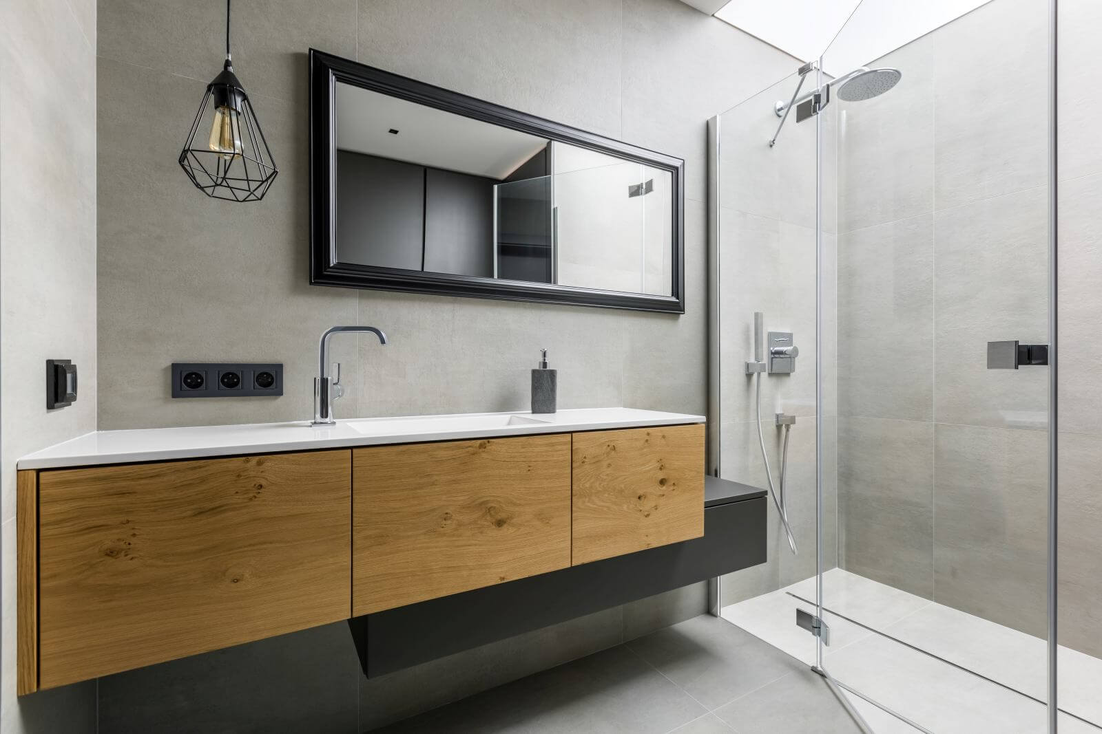 Modern, gray bathroom with walk in shower, mirror and countertop basin
