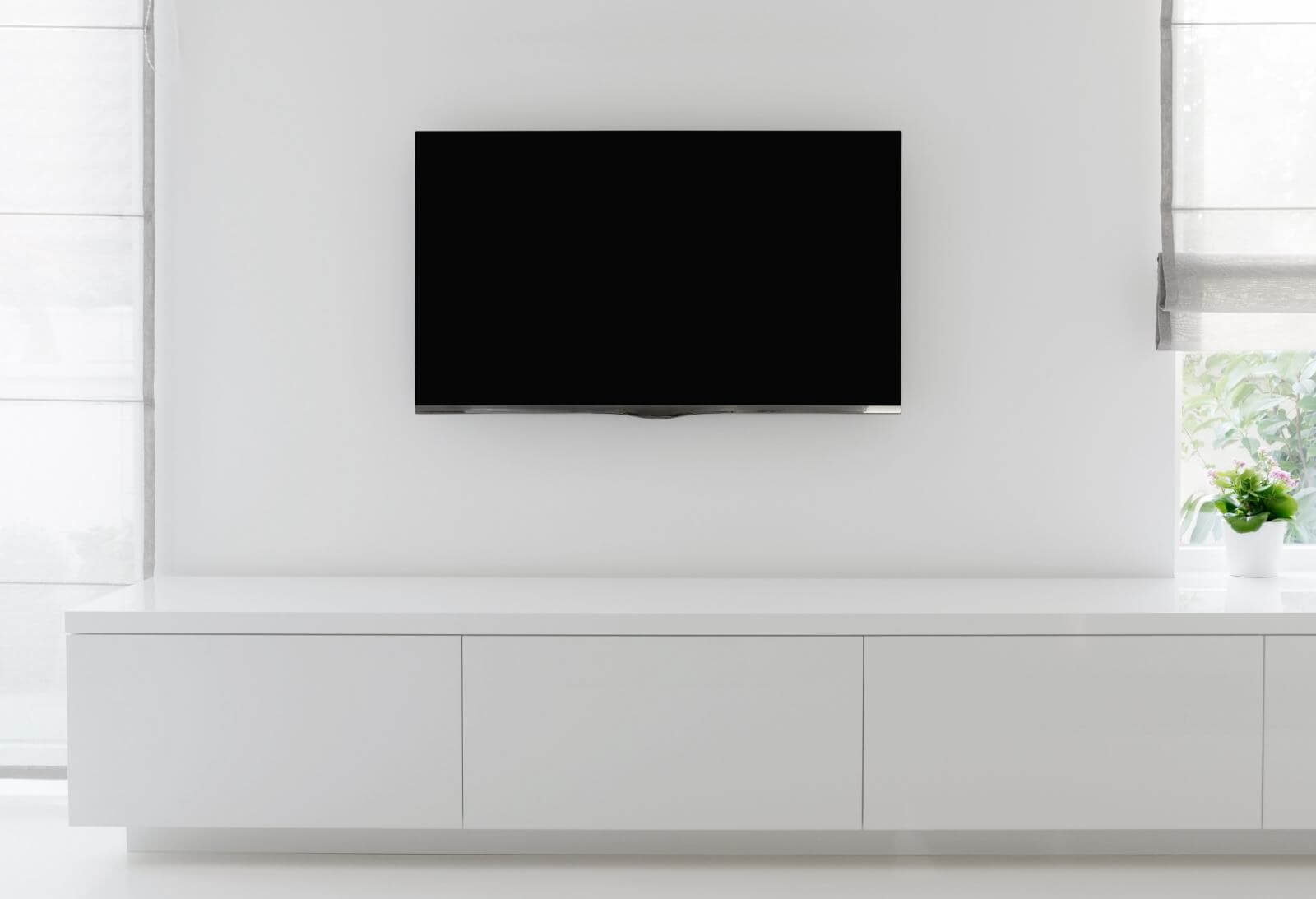 white living room detail tv on wall with commode and epoxy flooring