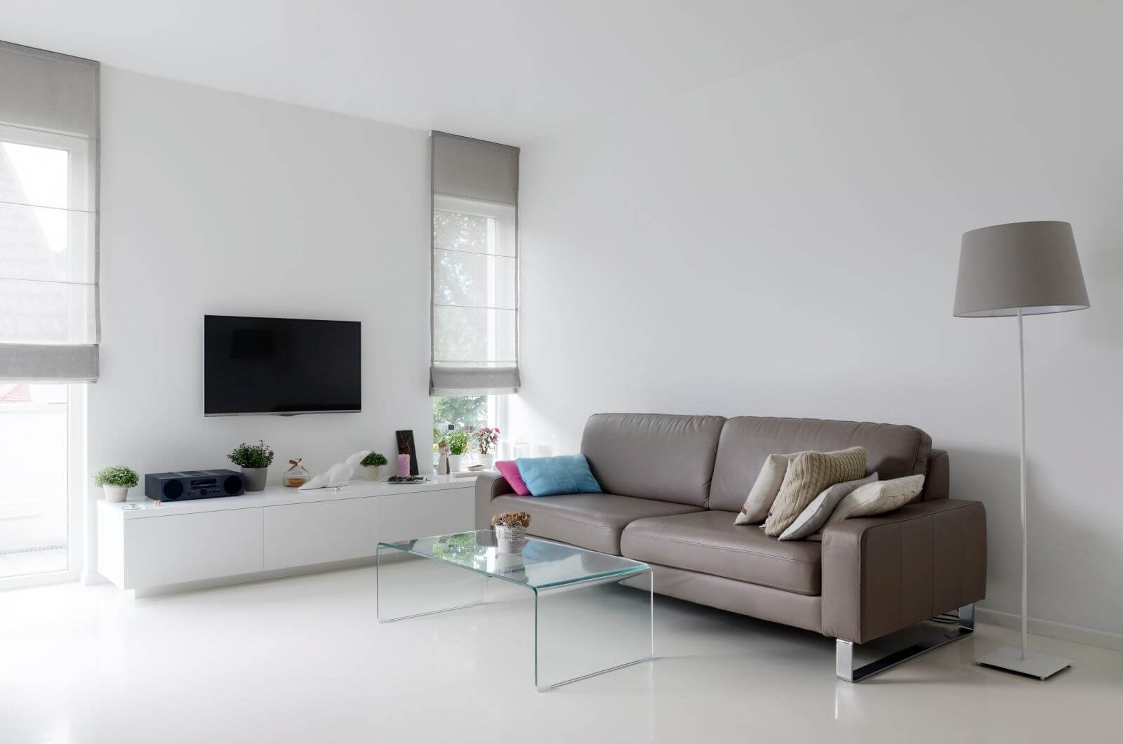 White living room with taupe leather sofa and glass table