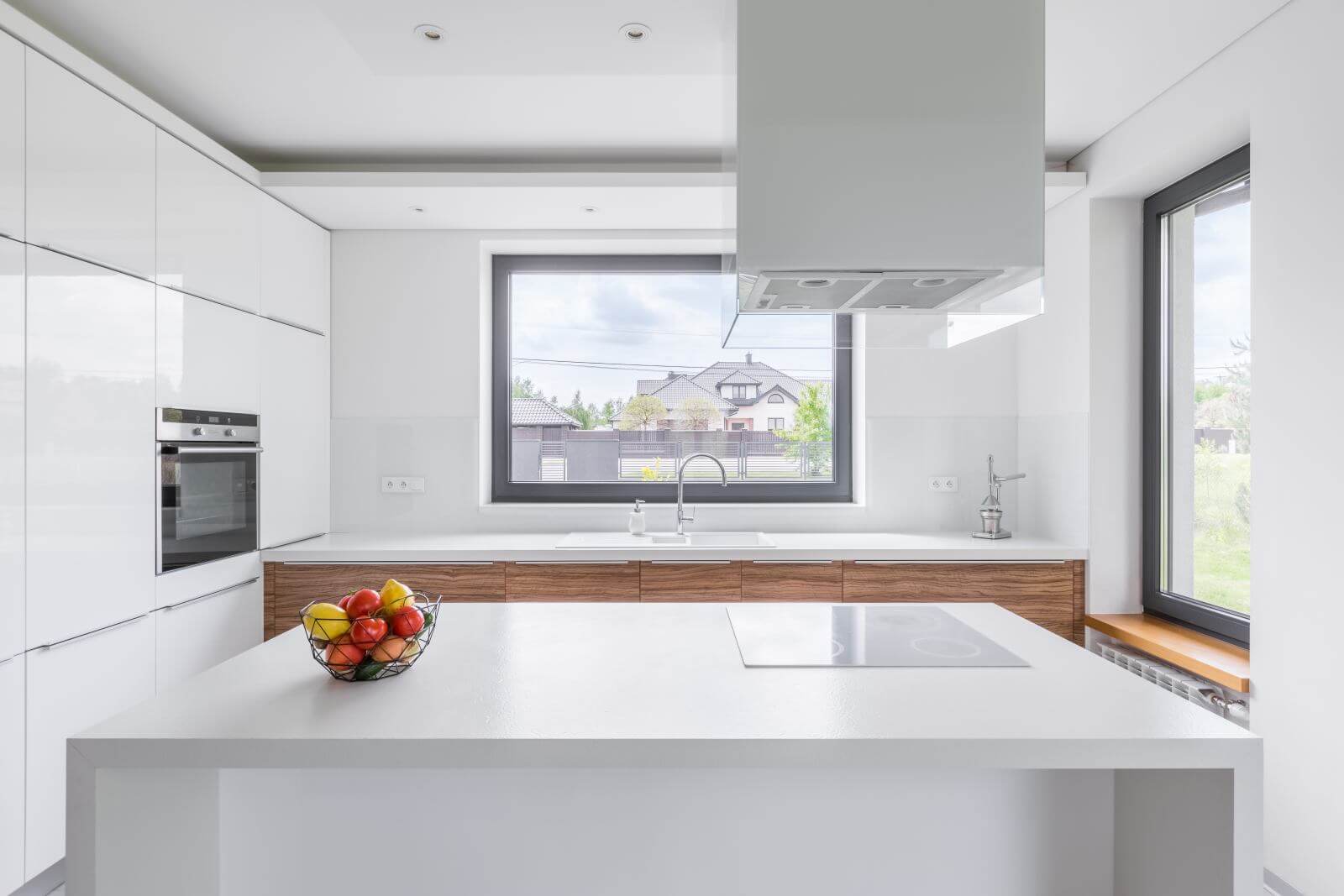 White kitchen with modern island, window and wooden cupboards