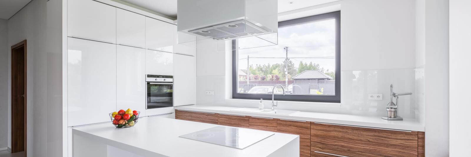 Panoramic view of modern, white kitchen with island and long countertop