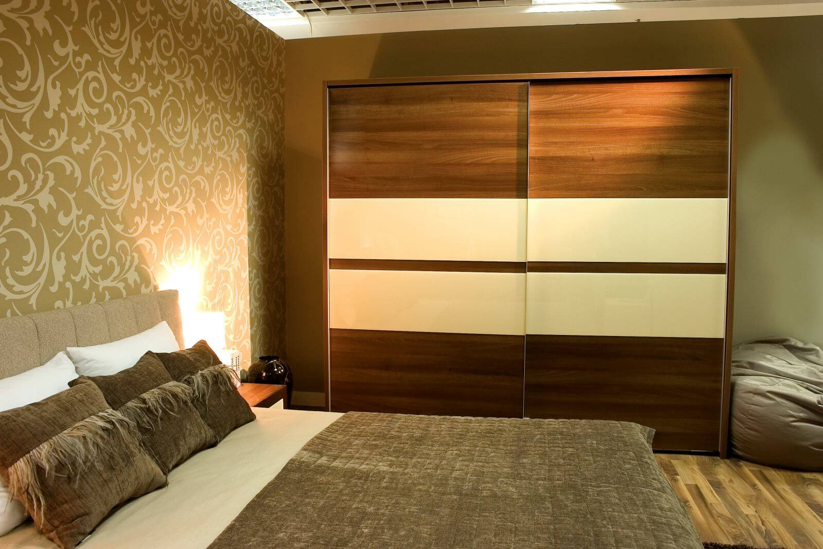 Modern bedroom with brown wardrobe and bed with two pillows.