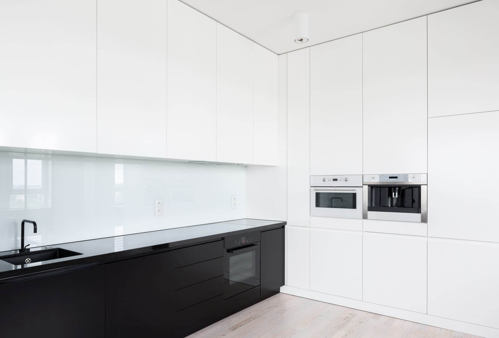 Elegant black and white elegant kitchen with many cupboards and build in kitchen equipment