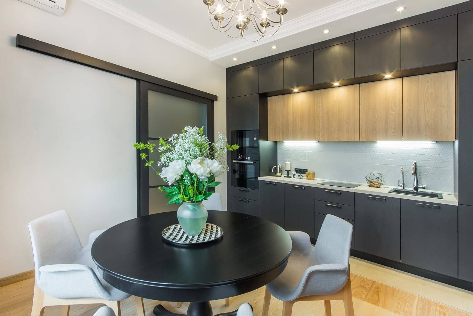 Beautiful kitchen in contemporary apartment. Modern interior with round breakfast table with flowers and sliding door