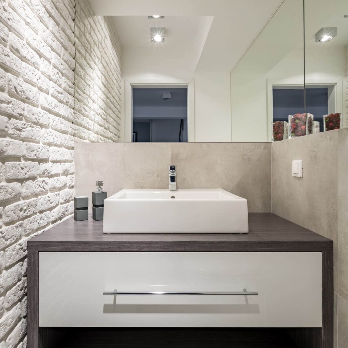 Bathroom with white brick tiles, mirror and countertop basin