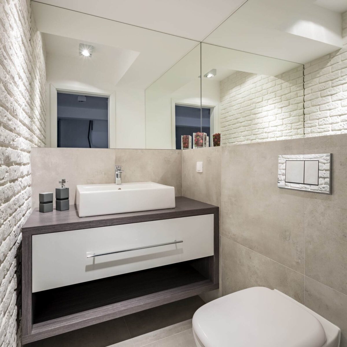 Modern bathroom with brick wall, toilet and basin cabinet