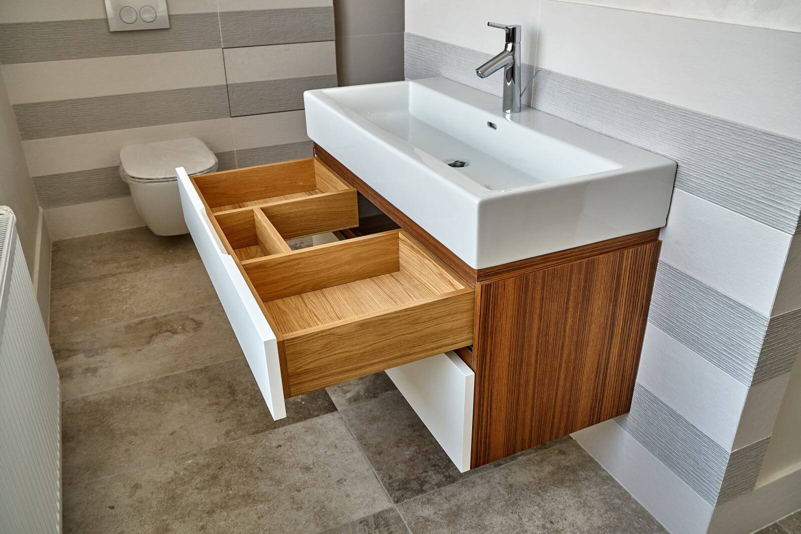 Bathroom console sink vanity in luxury bathroom with teak floor and striped tiles. Stylish interior of modern bathroom. Details furniture