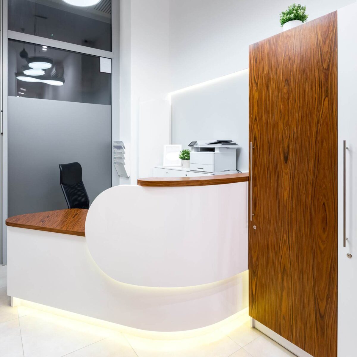 Bright and white office reception area with wooden desk